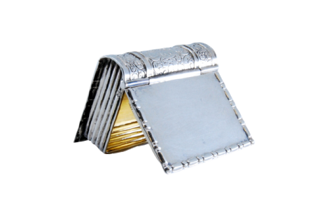 Caixa de comprimidos em prata em forma de livro com frisos gravados com interior dourado e tampa basculante.